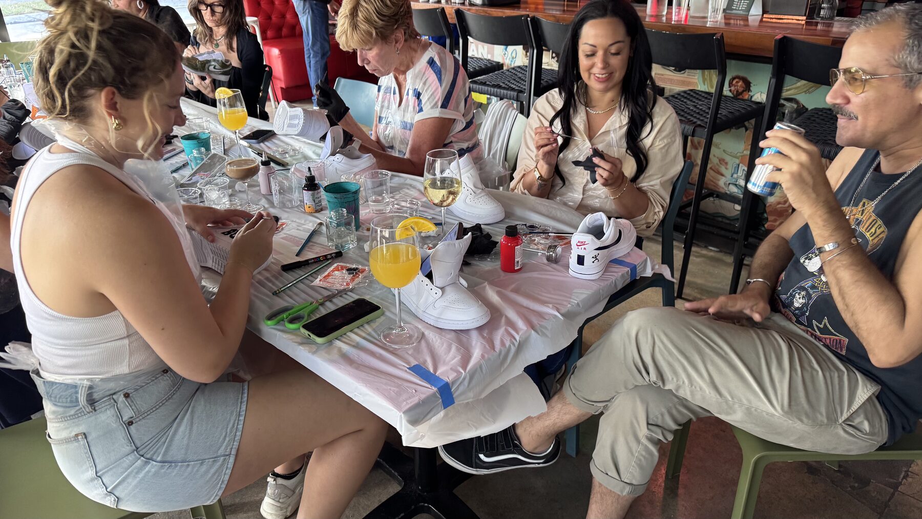 Friends customizing sneakers together with food and drinks available at Grails Miami