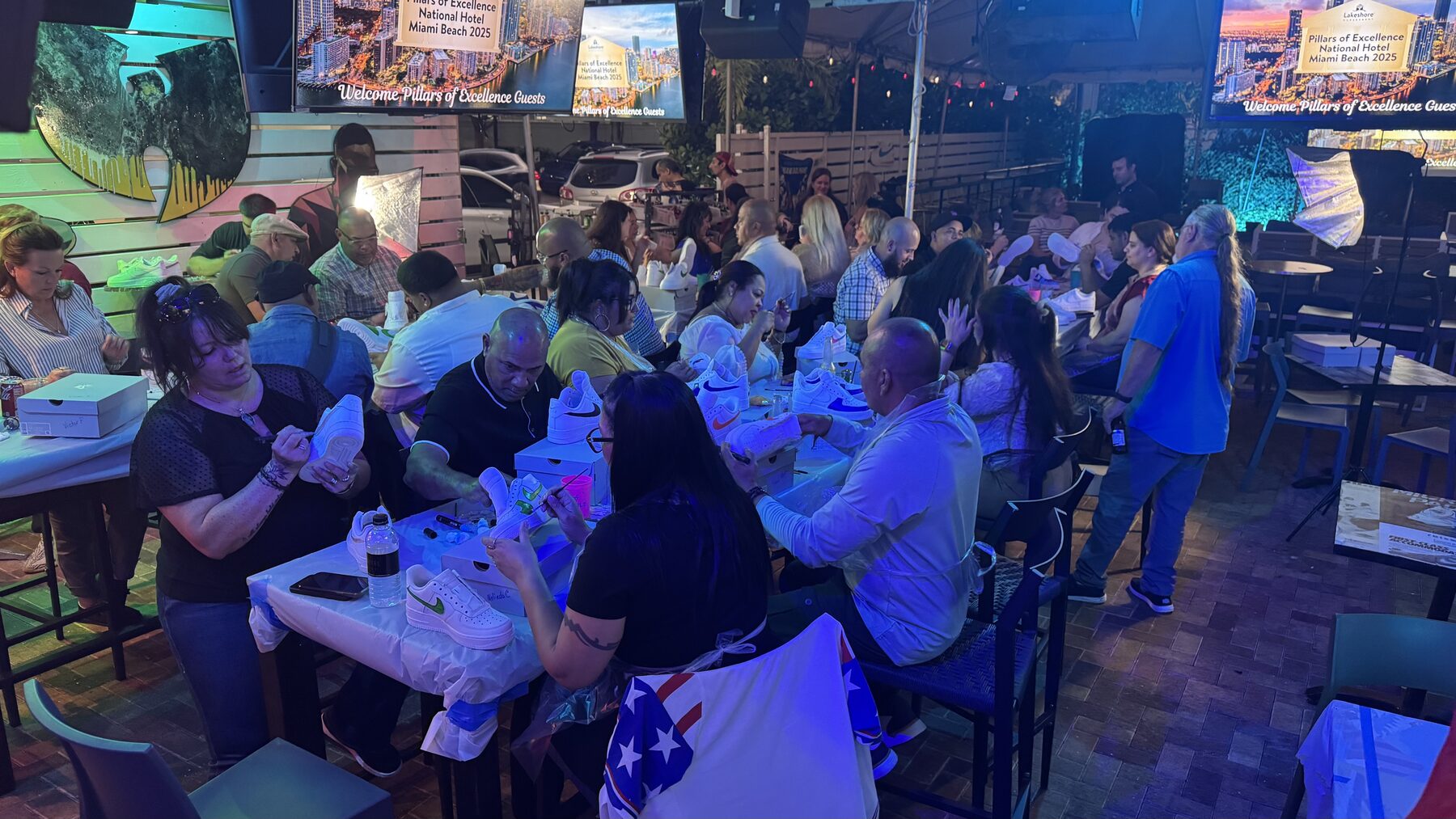 Large group enjoying a corporate team-building custom sneaker workshop in Miami