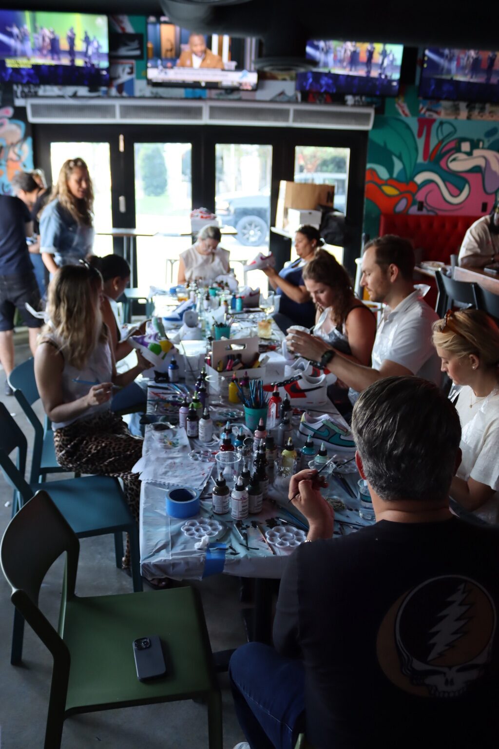 Corporate team building group painting custom sneakers at a Kick Art workshop in Miami
