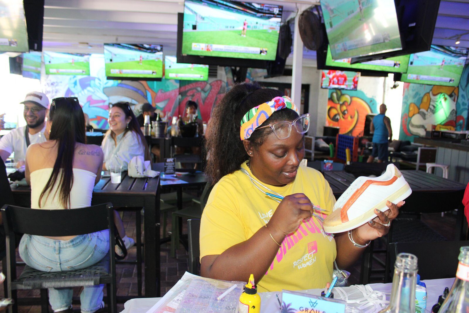 Woman painting her sneaker at a beginner-friendly Kick Art workshop in Wynwood